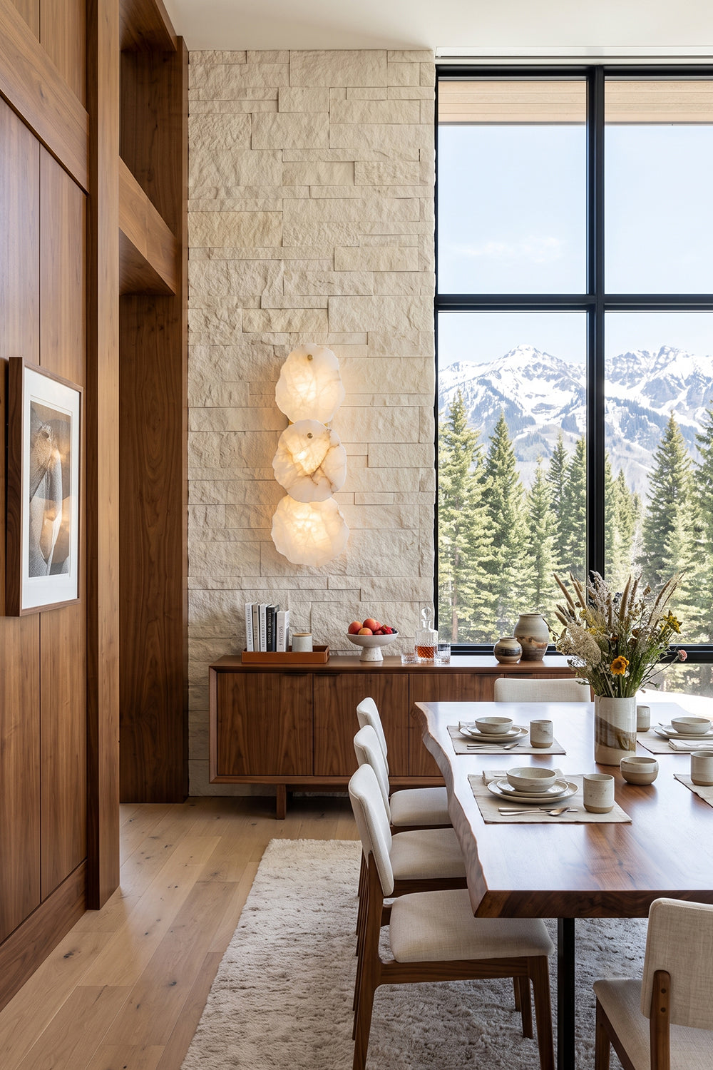 Corin Alabaster Wall Sconce illuminating a modern dining area with mountain views.