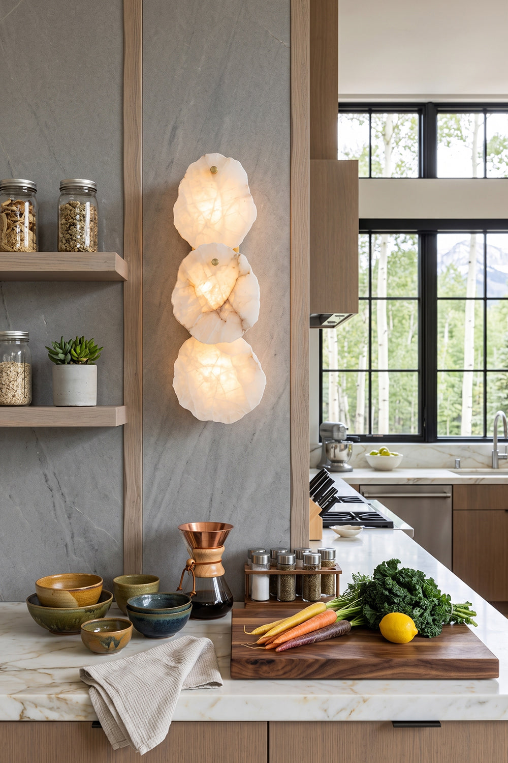 Corin Alabaster Wall Sconce illuminating a modern kitchen with natural stone and wooden accents.