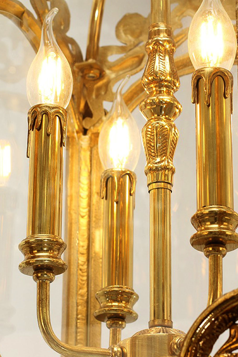 Corwin Glazed Brass Pendant Light close-up view showcasing elegant brass details and glowing candle-style bulbs.
