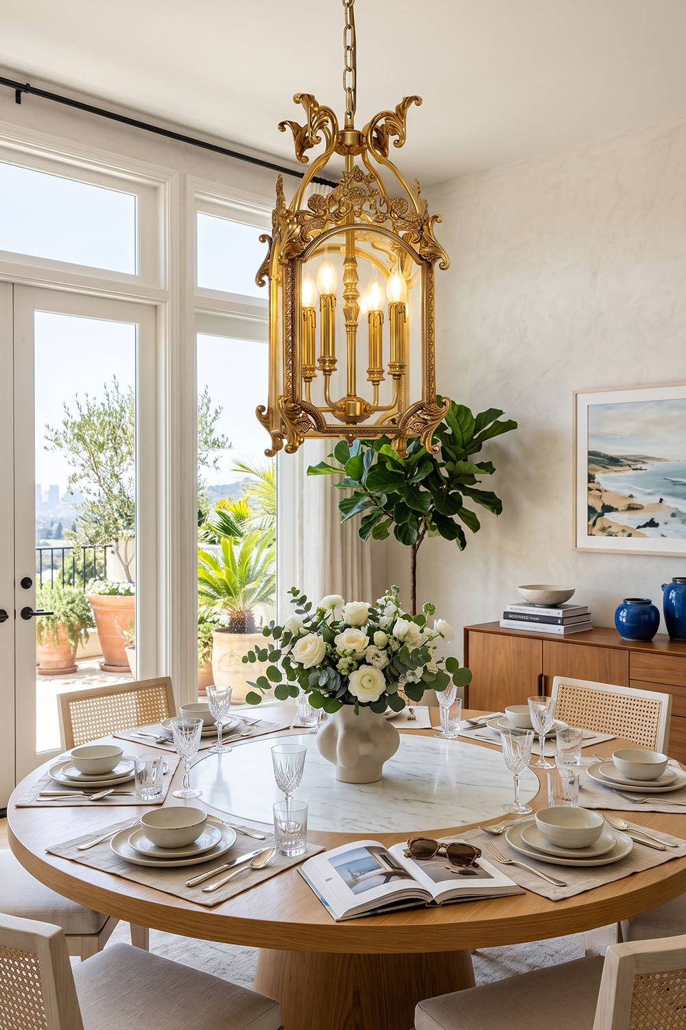 Corwin Glazed Brass Pendant Light hanging above a beautifully set dining table with flowers and greenery in a stylish room.