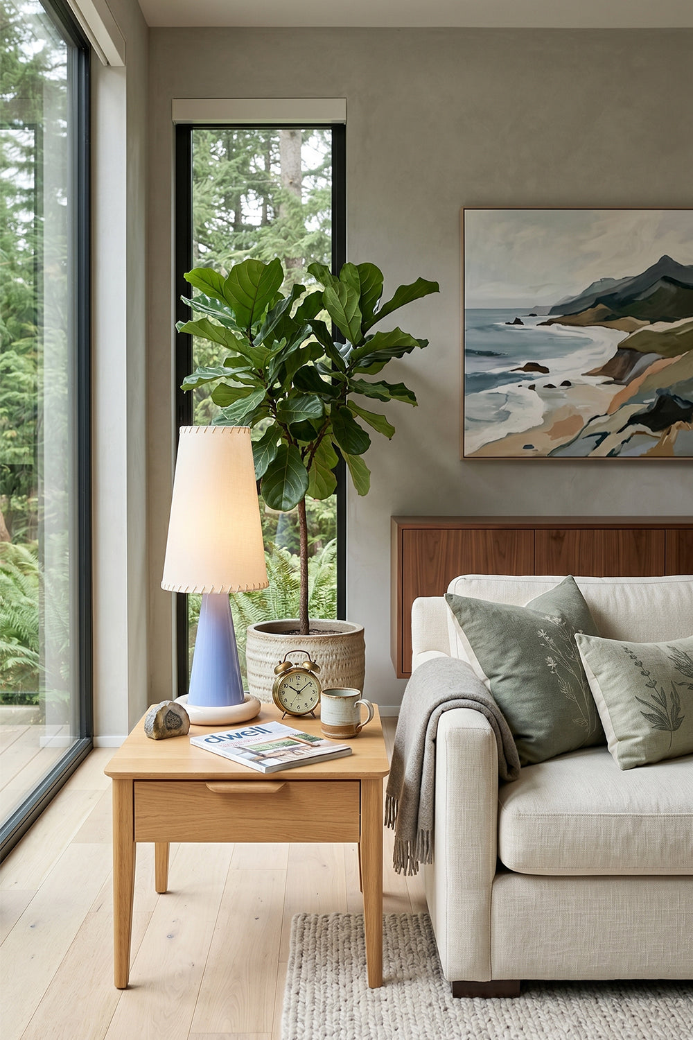 Dolce Ribbon Ceramic Table Lamp | Ceramic, Fabric | Positioned on a light oak side table next to a cream fabric couch and indoor green trees in a bright modern living room | Samu Lamp
