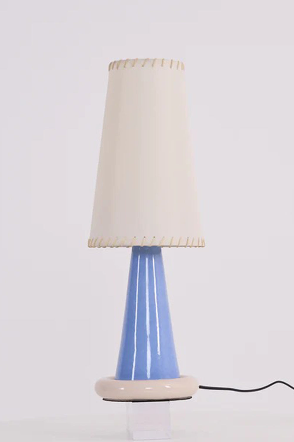 Dolce Ribbon Ceramic Table Lamp | Ceramic, Fabric | Unlit studio view of the tall white shade variant showing the clean periwinkle blue ceramic cone base against a plain light background | Samu Lamp