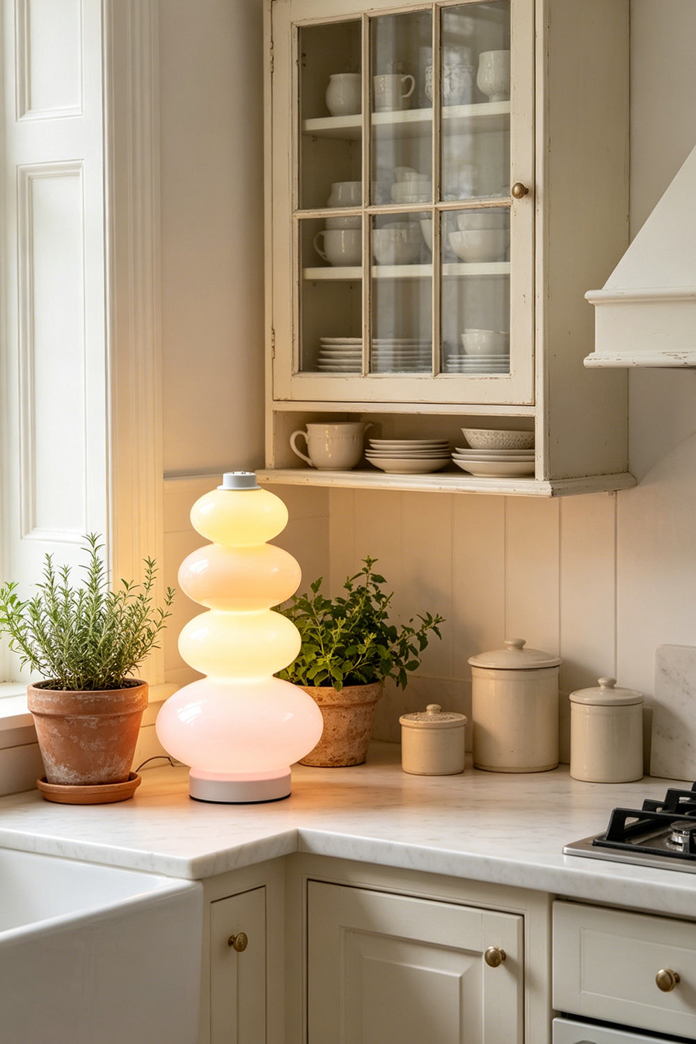 Dolce Stacked Pastel Glass Table Lamp | Glass, Metal | Placed on a classic white kitchen counter next to terracotta herb pots and traditional cabinetry | Samu Lamp