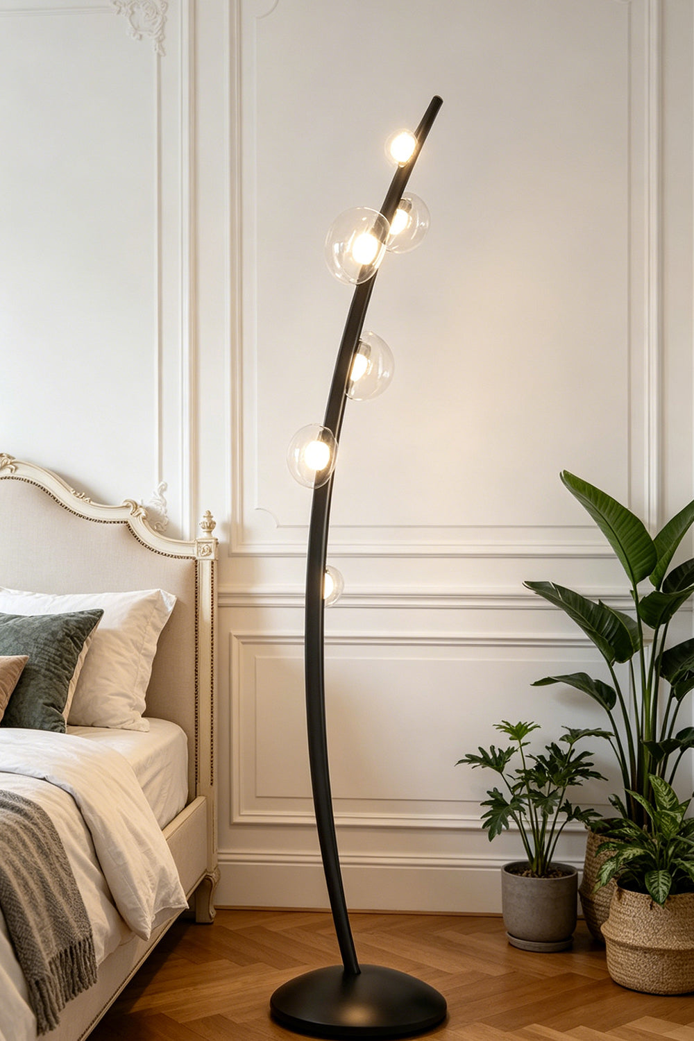Drosia Dewdrop Floor Lamp | Glass, Metal | Standing elegantly as a modern reading light in a cozy bedroom corner next to a platform bed and indoor potted plants | Samu Lamp