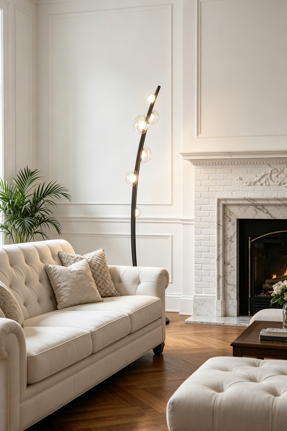 Drosia Dewdrop Floor Lamp | Glass, Metal | Casting a welcoming glow in a sophisticated living space corner next to a cream fabric sofa and a classic fireplace mantle | Samu Lamp
