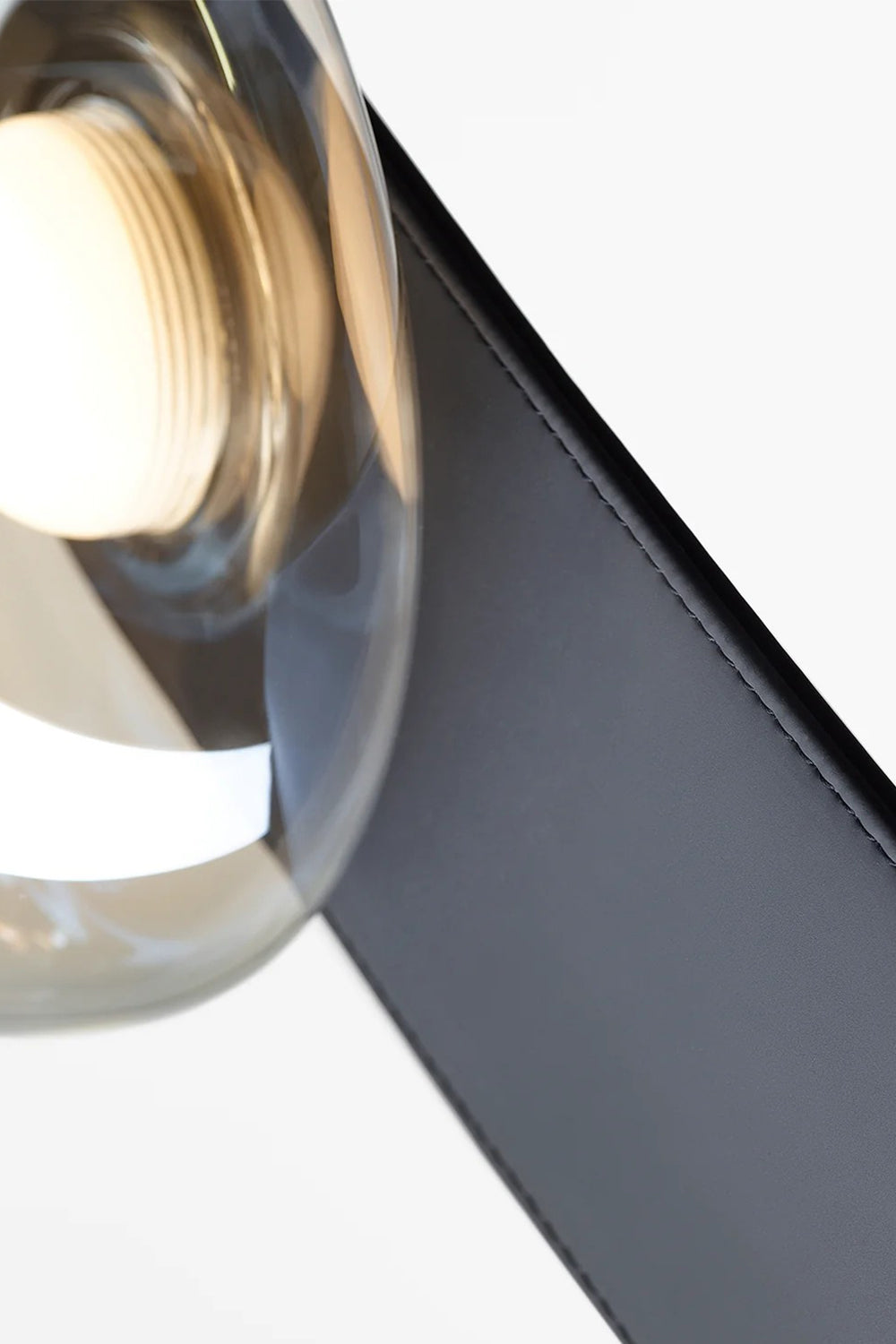 Drosia Dewdrop Floor Lamp | Glass, Metal | Macro close-up structural view showing a single transparent glass sphere seamlessly meeting the curved edge of the matte black metallic stem | Detail shot | Samu Lamp