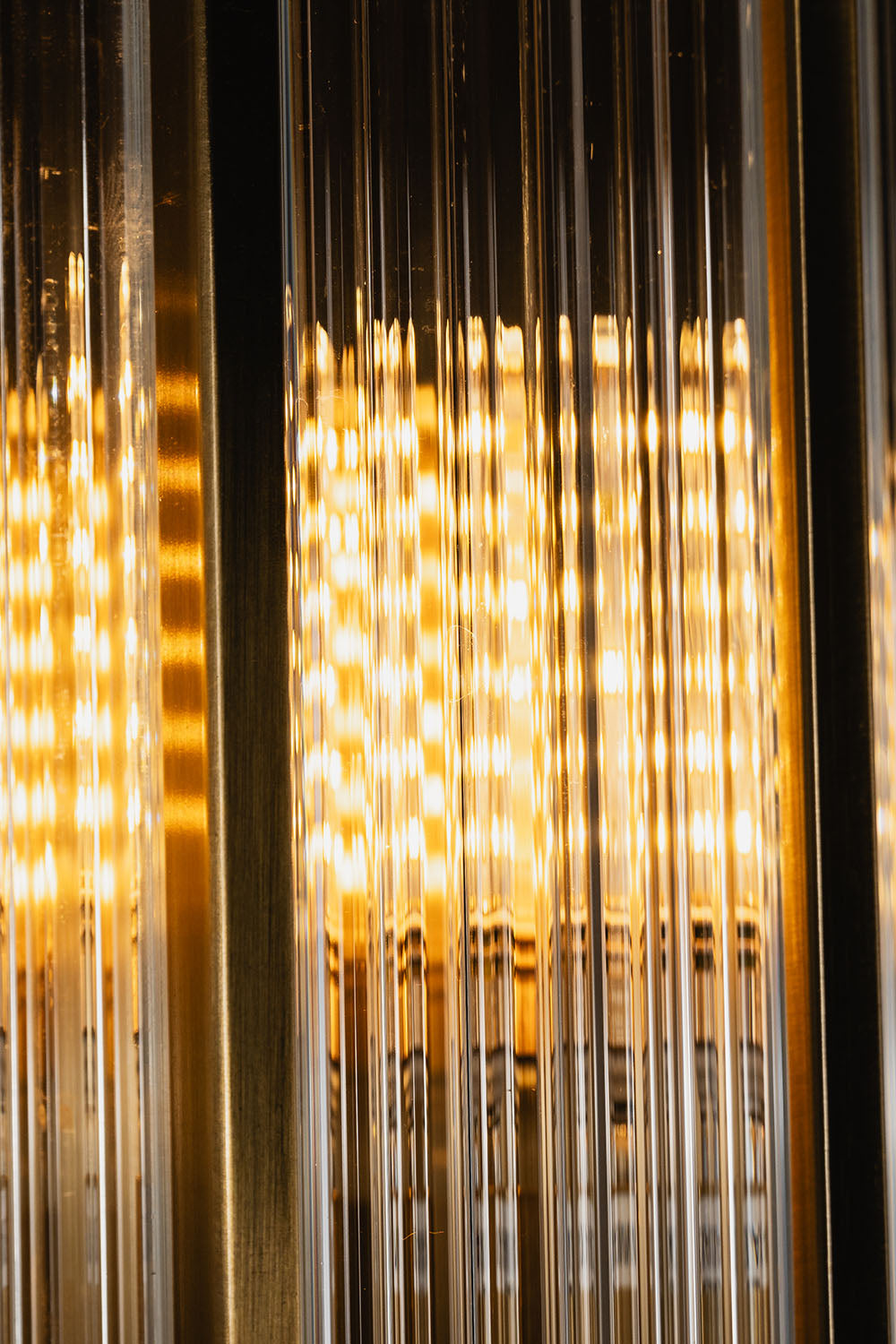 Close-up of the warm lighting and ribbed glass design of the Drystan Ribbed Glass Brass Wall Lamp.