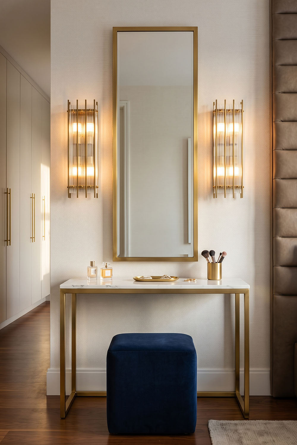 Stylish vanity area featuring Drystan Ribbed Glass Brass Wall Lamp on either side of a large mirror.