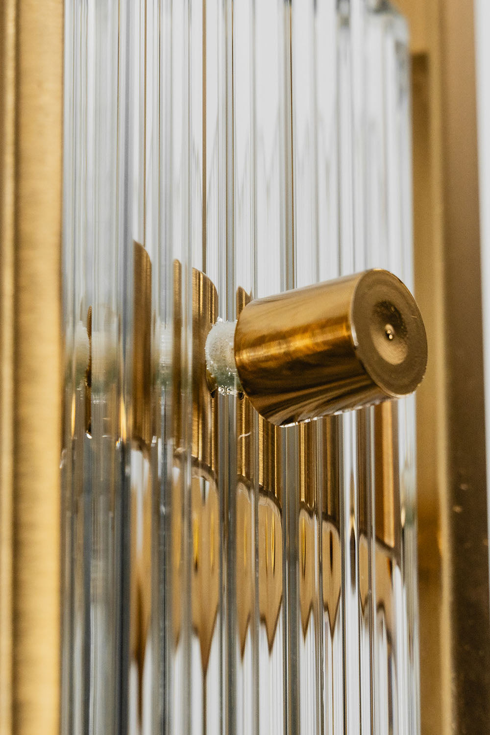 Close-up of the Drystan Ribbed Glass Brass Wall Lamp showcasing the brass detail and ribbed glass design.