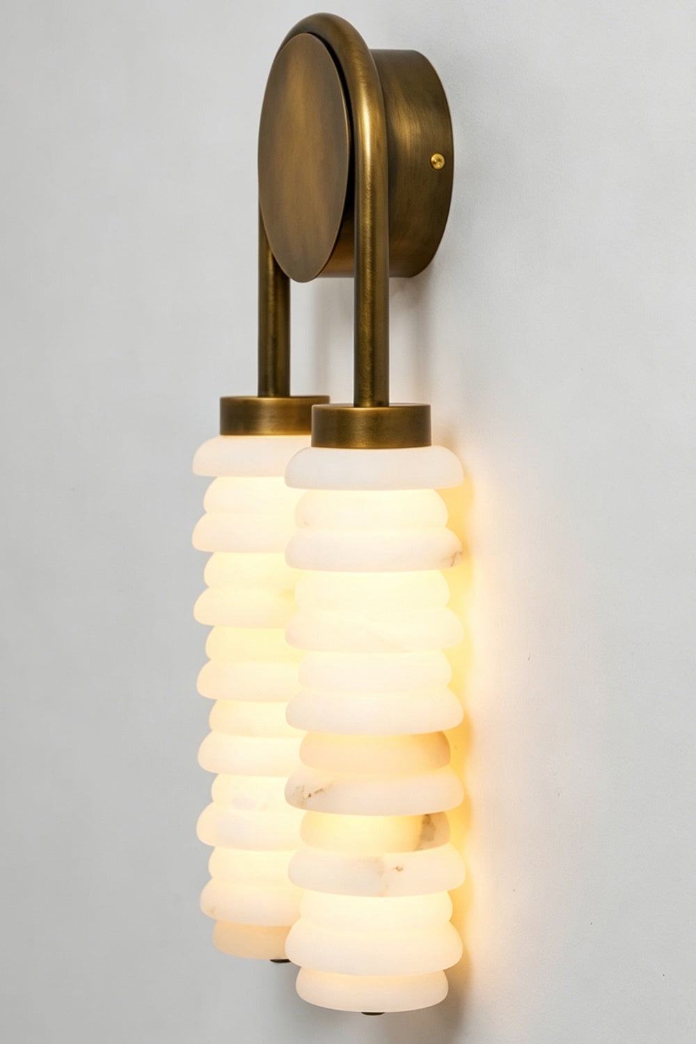 Dual Strata Alabaster Wall Lamp | Metal, Alabaster | Lit perspective detail shot against a neutral grey wall, showing stone texture | Samu Lamp