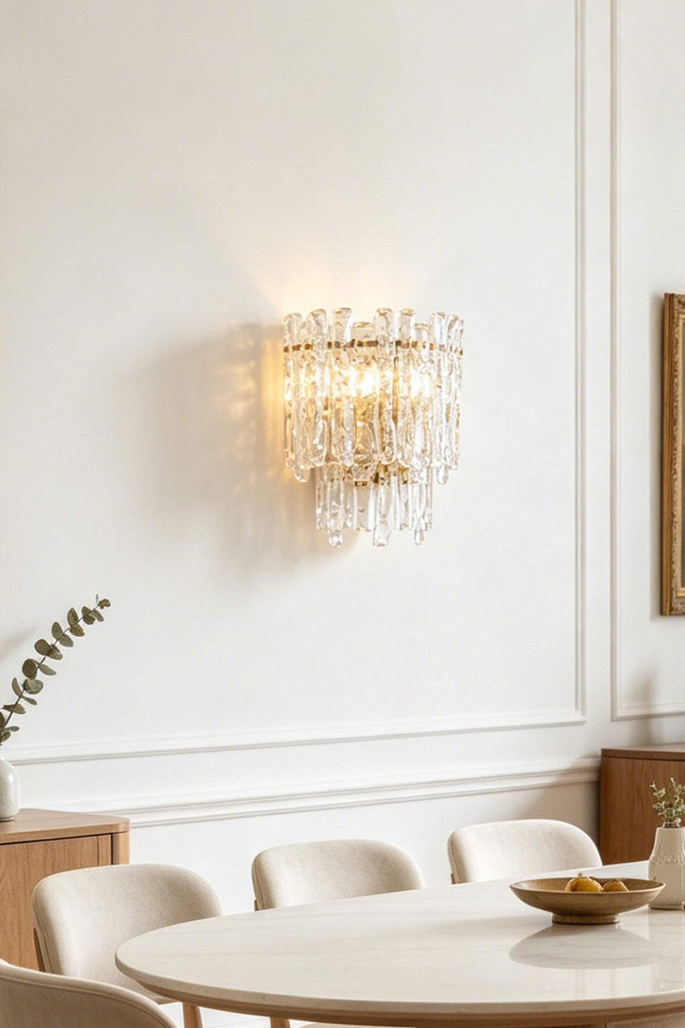 Elara Textured Cast Glass Wall Lamp | Textured Cast Glass, Polished Brass | Close-up view of the illuminated lamp installed on a wall, highlighting the intricate pattern and warm, diffused light filtered through the artisanal glass panels | Samu Lamp