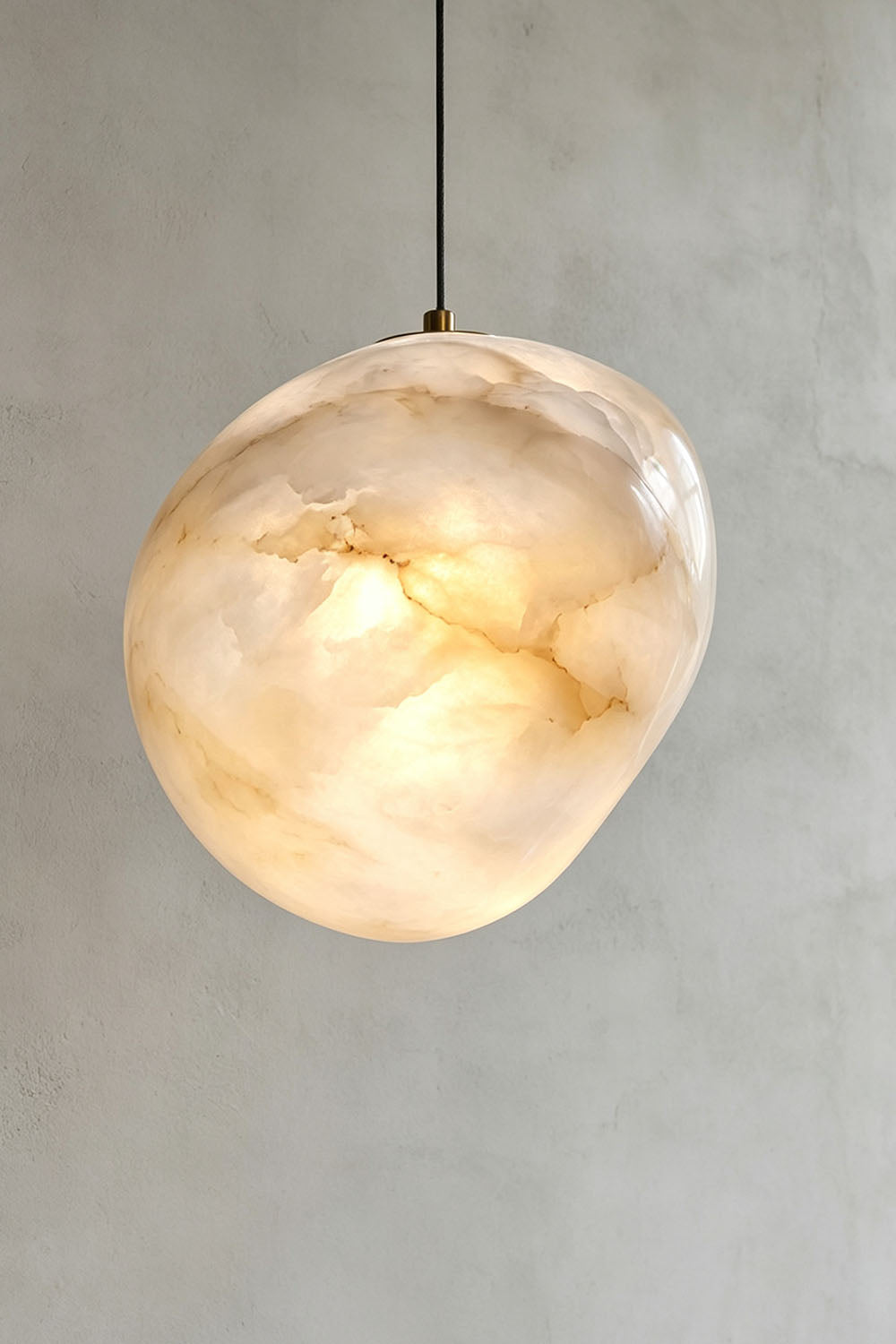 Elodie Teardrop Alabaster Pendant Light hanging from the ceiling, showcasing its organic shape and unique design.