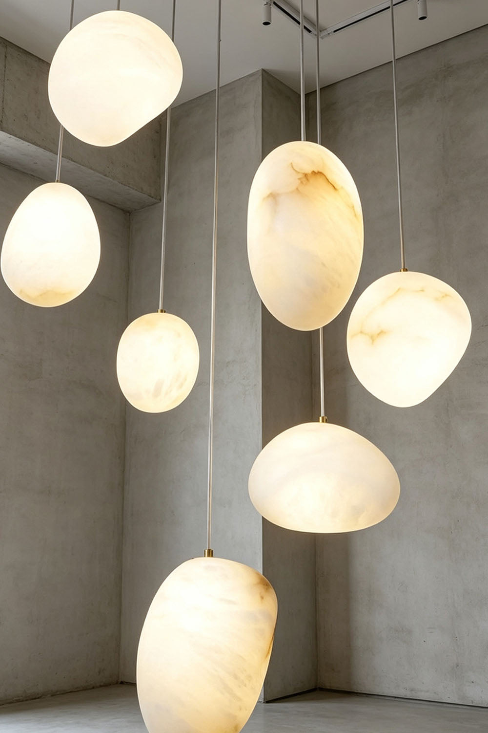 Elodie Teardrop Alabaster Pendant Light hanging in a modern interior setting showcasing unique shapes and warm glow.
