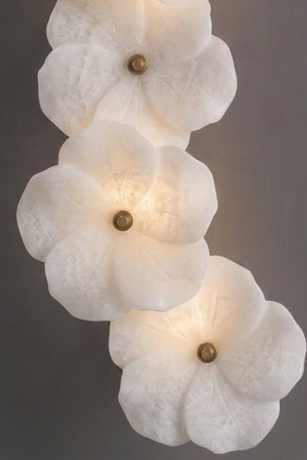 Elowen Alabaster Blossom Wall Light | Floral Detail | Detailed close-up shot focusing on three illuminated alabaster flower petals showcasing translucent texture and central brass pins | Detail shot | Samu Lamp