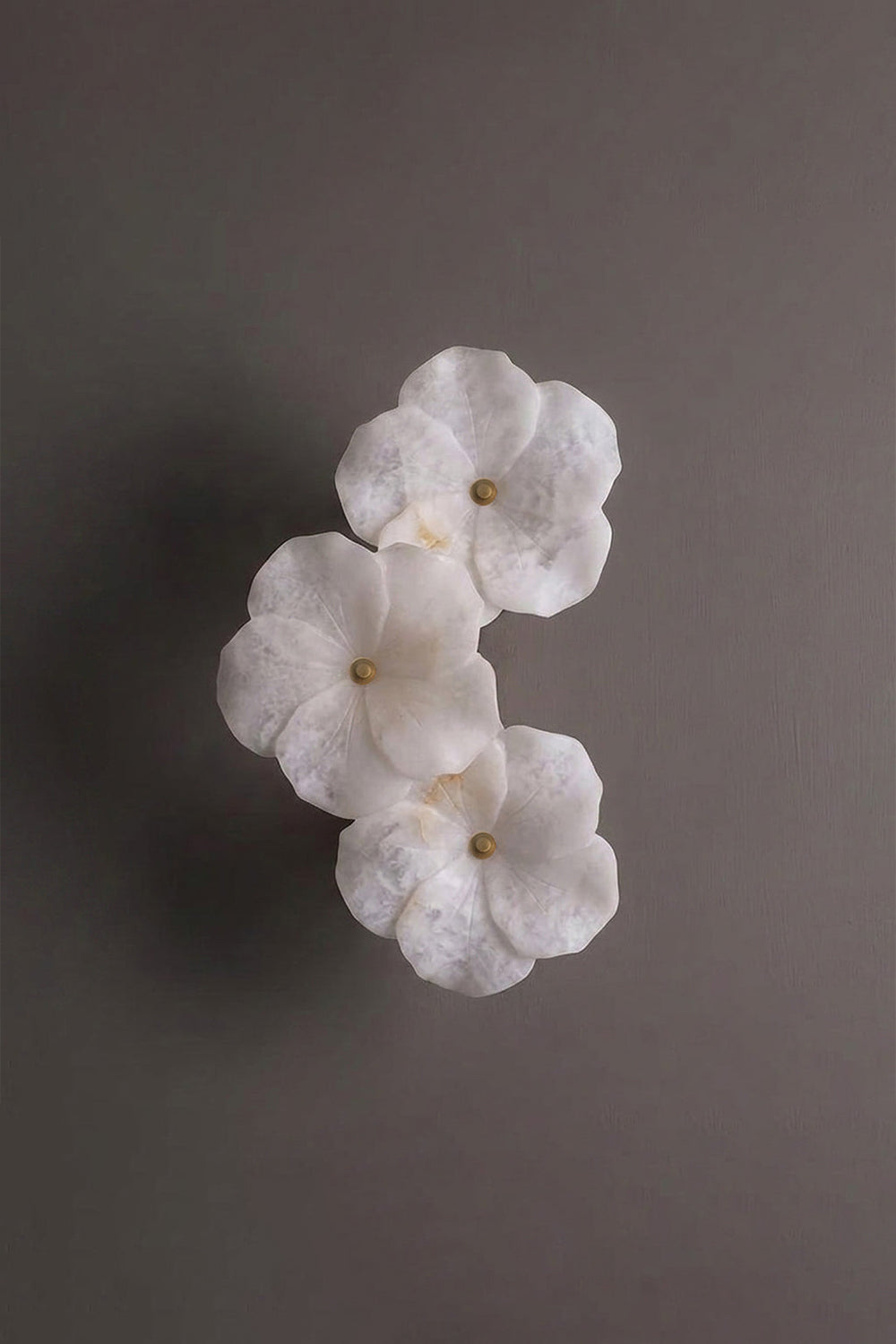 Elowen Alabaster Blossom Wall Light | Studio Profile View | Angled profile studio view of the unlit multi-flower sculptural stone wall fixture against a plain background wall | Samu Lamp