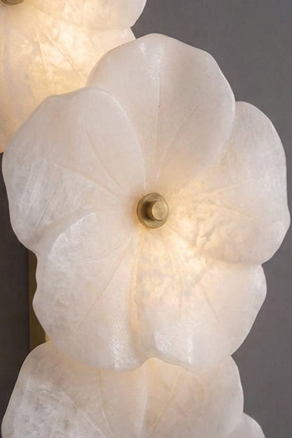 Elowen Alabaster Blossom Wall Light | Translucent Stone Detail | Macro close-up view of a single fully lit alabaster blossom highlighting cloudy mineral vein textures and the gold pin | Detail shot | Samu Lamp