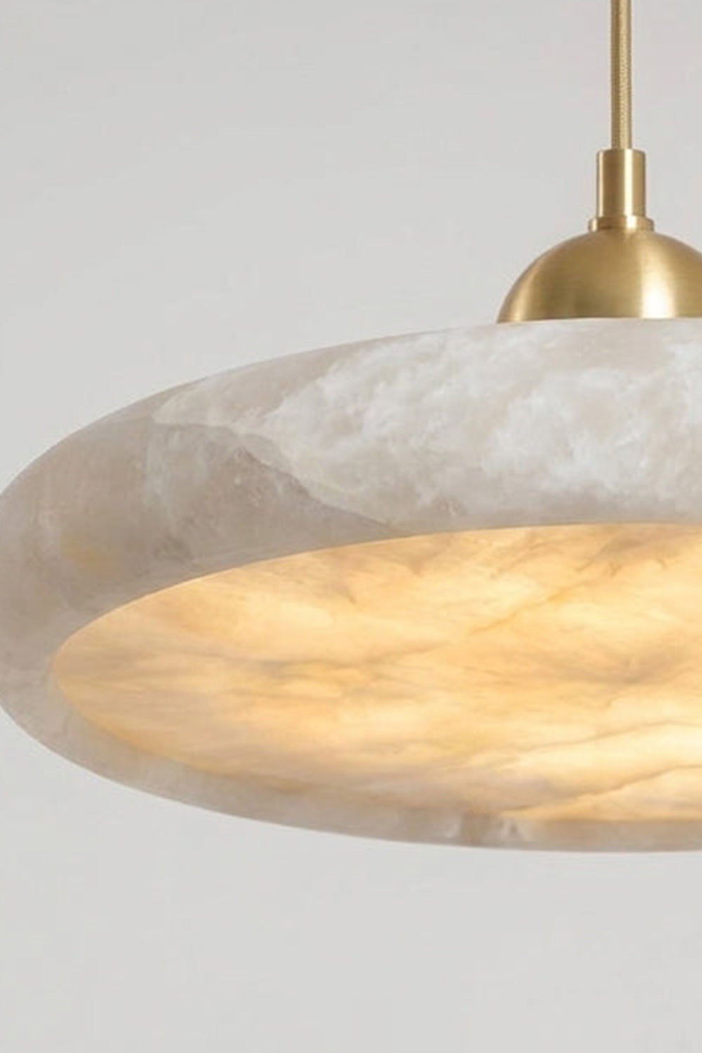 Elowen Alabaster Disc Pendant Light| Natural Alabaster and Brass | Close-up side view highlighting the warm ambient glow radiating from the heavy stone disc fixture | Samu Lamp