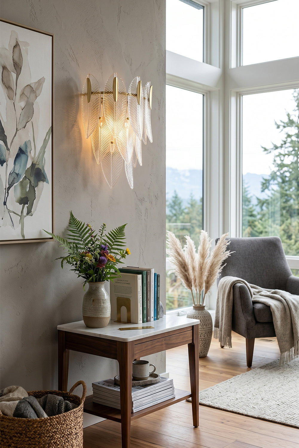Elowen Cascading Glass Wall Lamp | Glass, Metal | Providing a warm ambient glow on a wall next to a stylish end table with flowers, a grey lounge armchair, and pampas grass | Samu Lamp