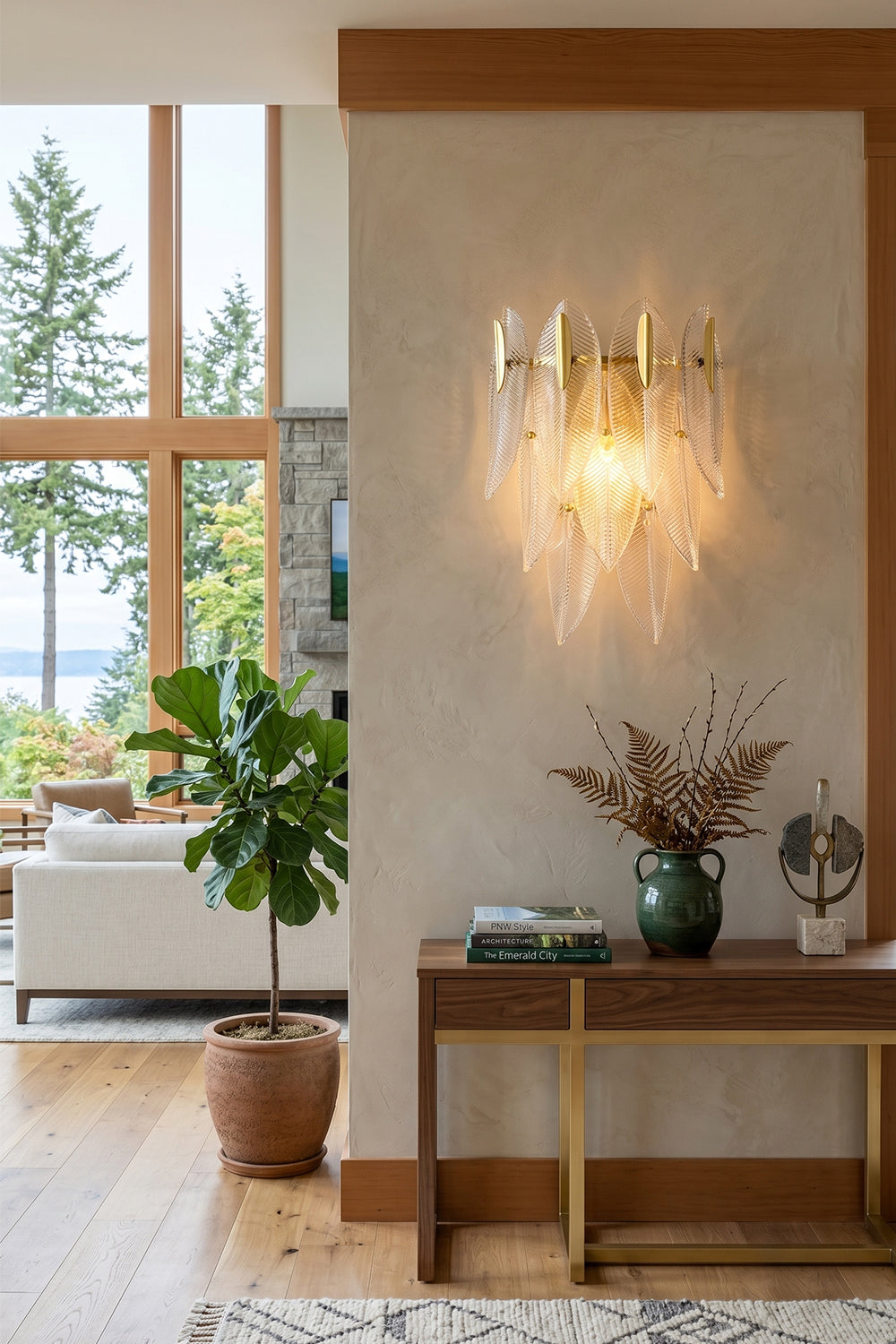 Elowen Cascading Glass Wall Lamp | Glass, Metal | Positioned elegantly on a pillar wall in a modern open-concept living space next to a wooden console table and a green potted plant | Samu Lamp