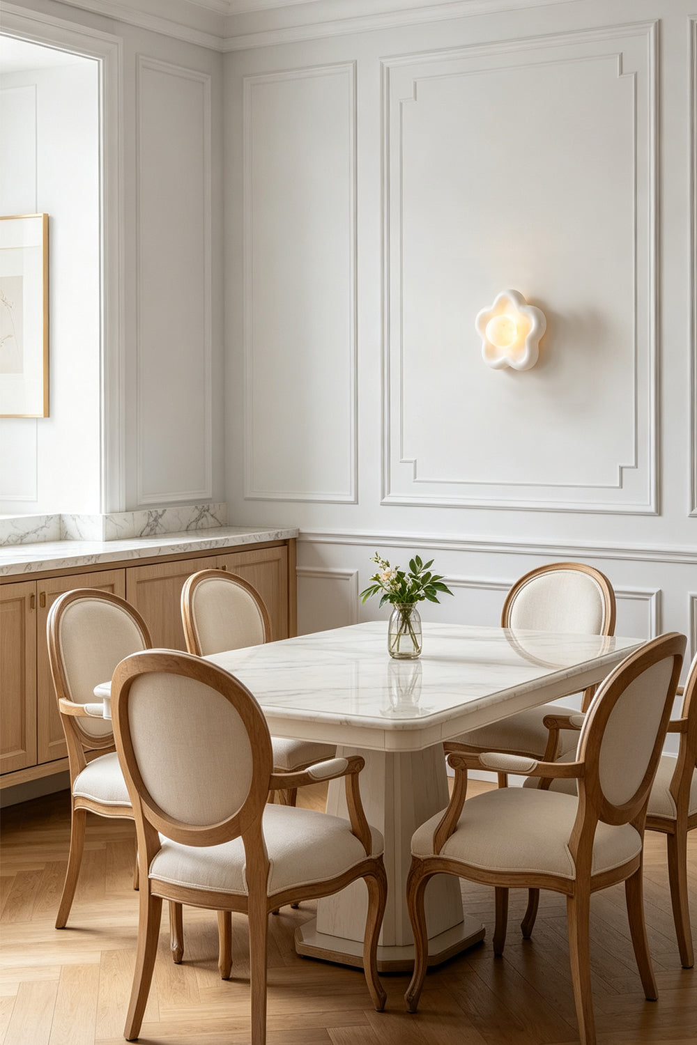 Elowen Petal Alabaster Wall Sconce | Natural Alabaster | Illuminating a minimalist white dining room space above a clean dining table and matching chairs | Samu Lamp