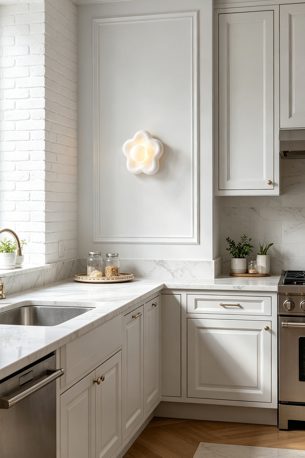 Elowen Petal Alabaster Wall Sconce | Natural Alabaster | Fixed on a bright kitchen wall casting a glow near white shaker cabinets and a sink counter | Samu Lamp
