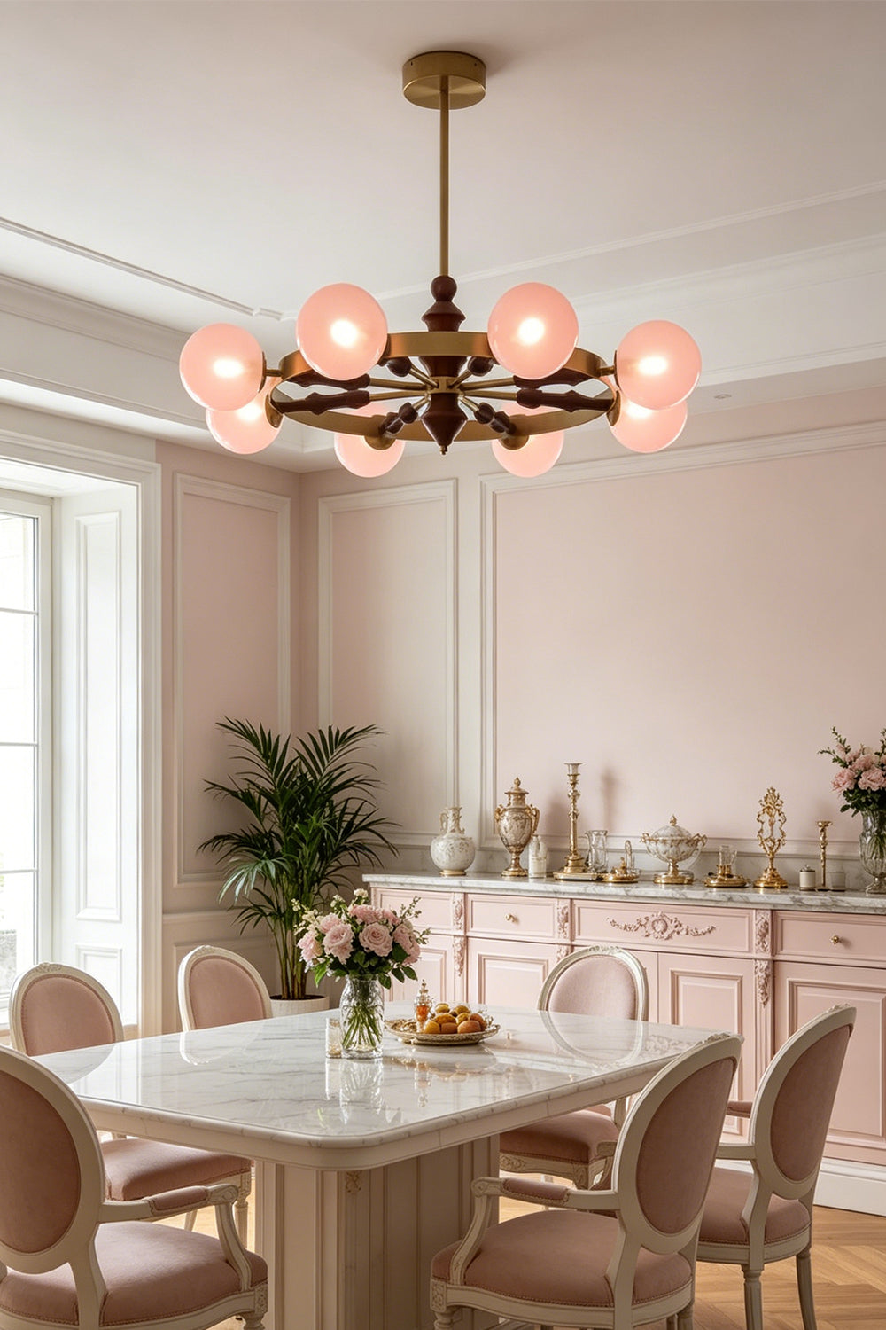Elysian Circlet Chandelier with pink globes over a dining table | Metal, Glass, Wood | Installed in a modern classic dining room with pink chairs | Samu Lamp
