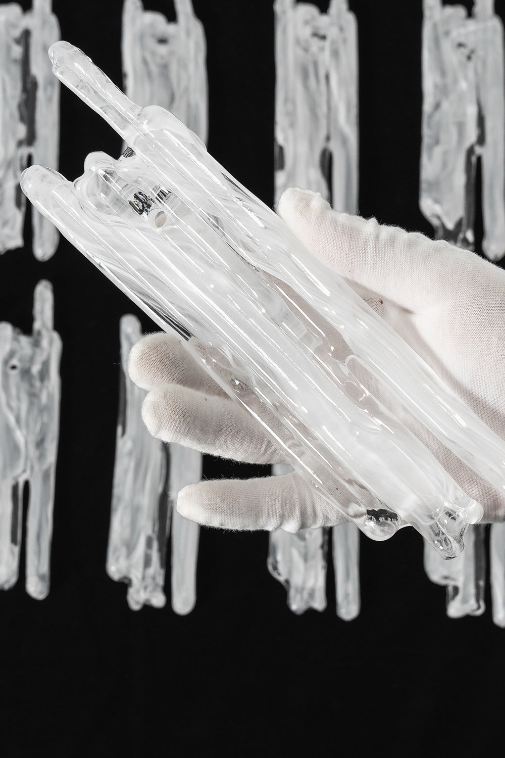 Ethereal Icicle Waterfall Chandelier | Glass, Metal | A gloved hand inspecting a single organic hand-blown glass panel to demonstrate its textured icicle design | Scale reference shot | Samu Lamp