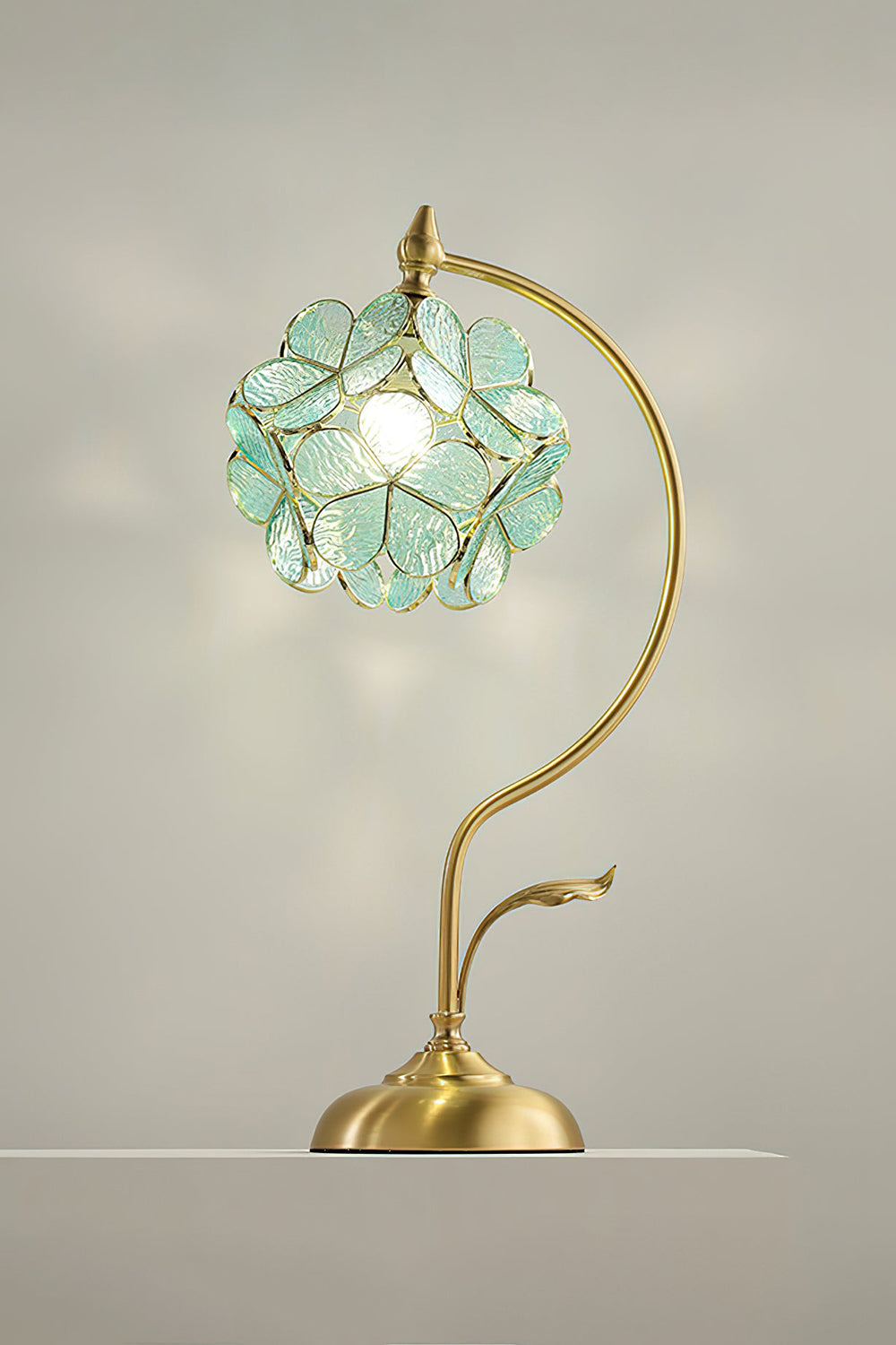 Evanthe Blossom Stained Glass Table Lamp | Stained Glass, Metal | Studio view of the mint green glass variant fully lit, projecting a soft botanical backlight halo on a plain neutral wall | Samu Lamp