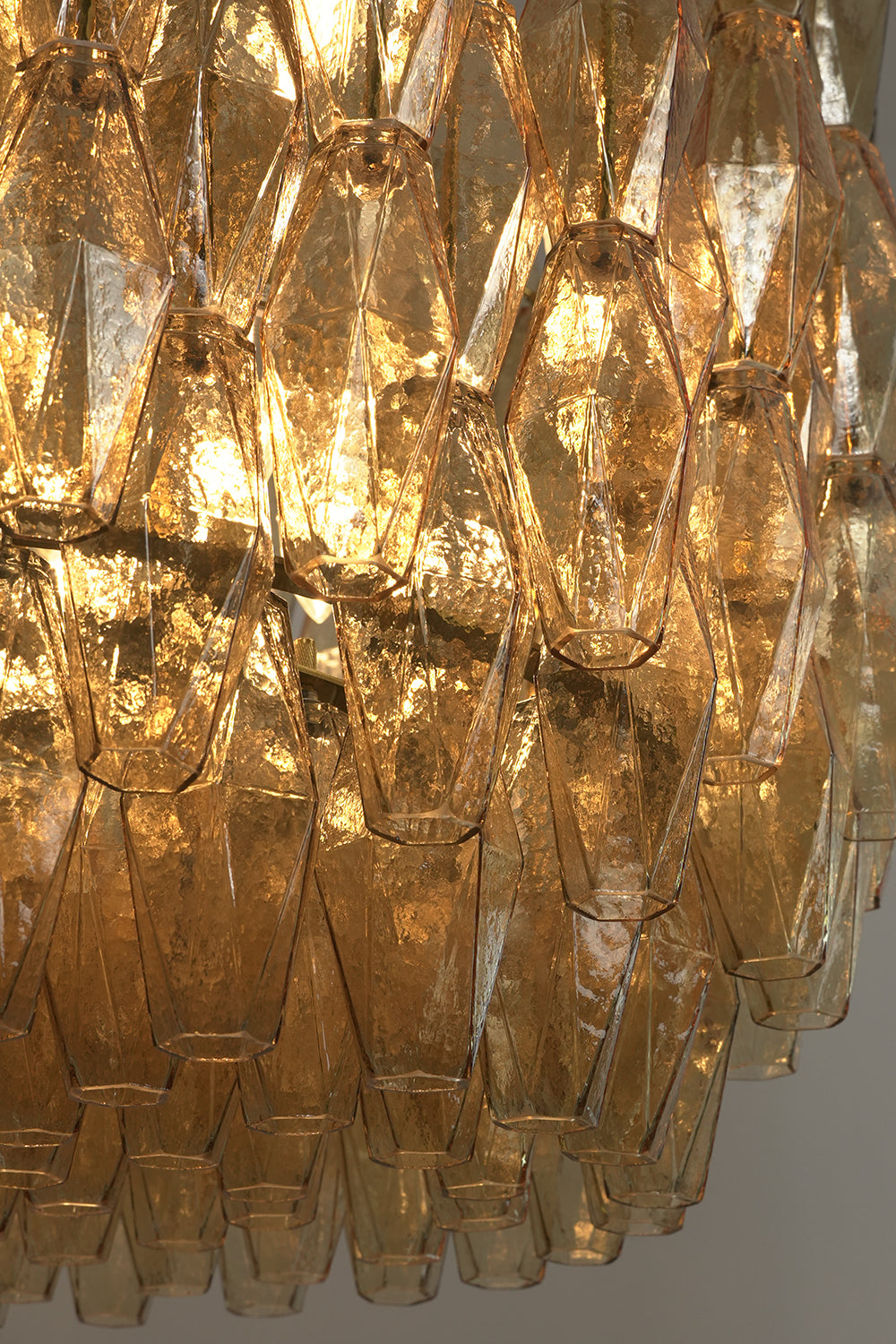 Low-angle view of lit amber glass chandelier | Metal, Glass | Showing the layered drum structure and warm light | Samu Lamp