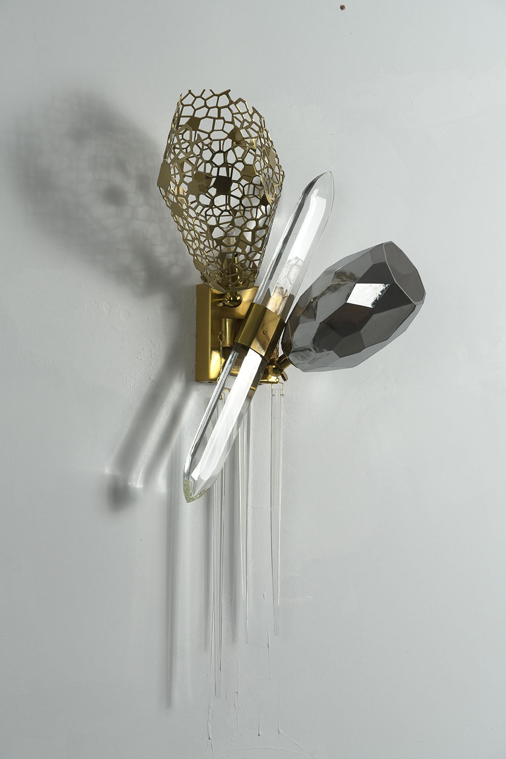 Faucenne Pierced Shade Crystal Spear Wall Lamp | Cut Crystal and Brass | Front product view mounted on a plain grey wall | Samu Lamp