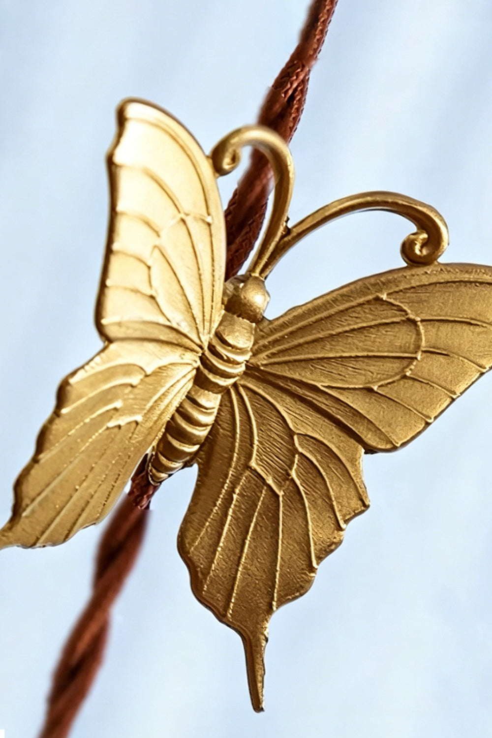 Faye Pastel Scalloped Glass Pendant Lamp | Glass, Metal | Macro close-up focus on the intricate details of the sculpted golden brass butterfly accent on the cord | Detail shot | Samu Lamp