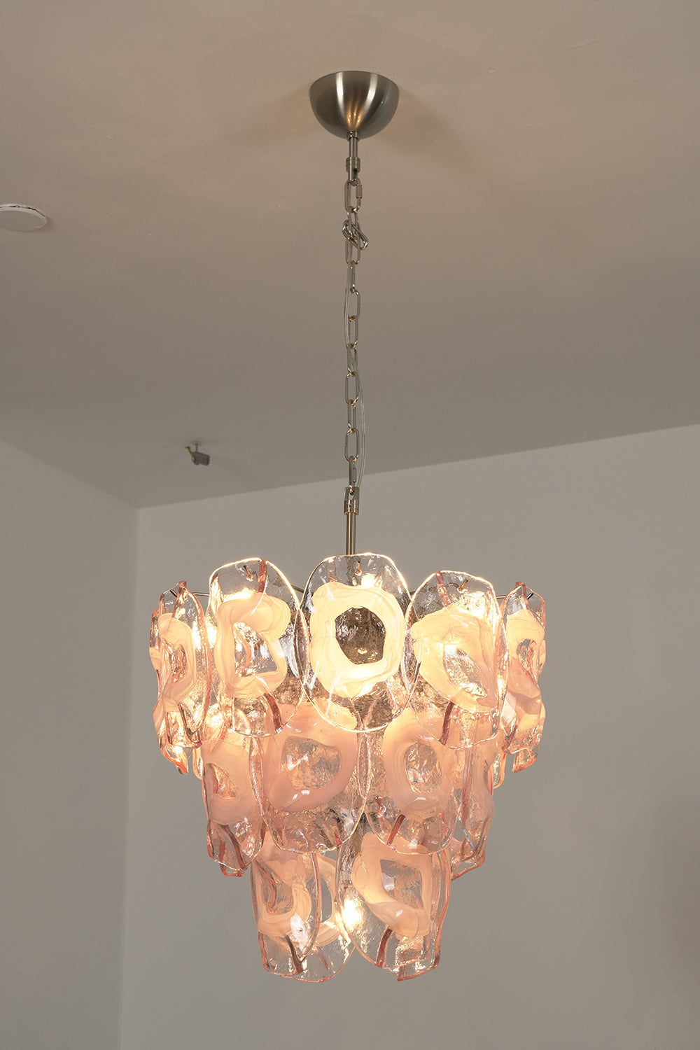Lit pink glass chandelier | Metal, Glass | Perspective view installed on a white ceiling | Samu Lamp