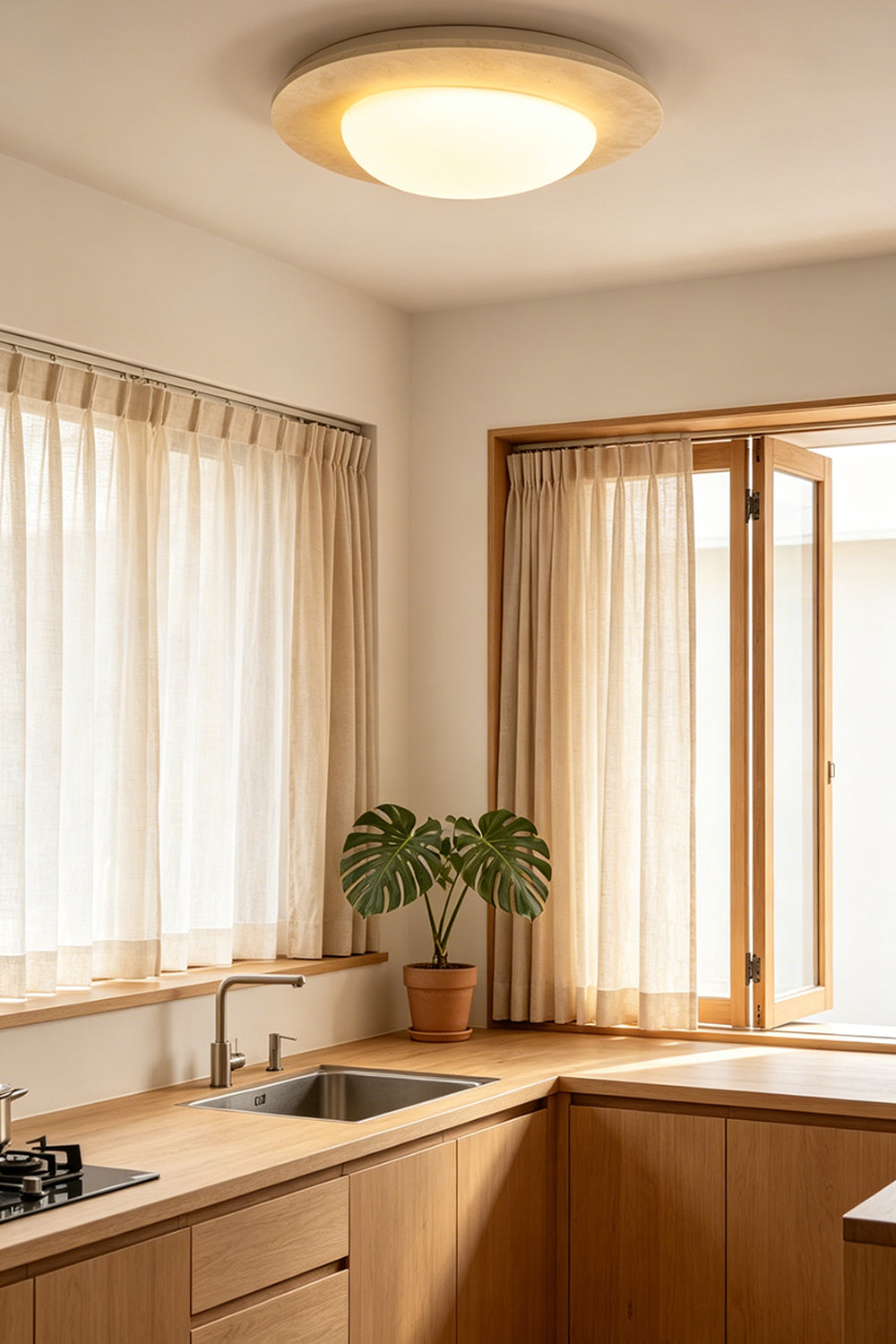 Geoidal Halo Travertine Ceiling Light | Travertine, Glass | Illuminated in a sunlit kitchen with wood cabinets | Samu Lamp