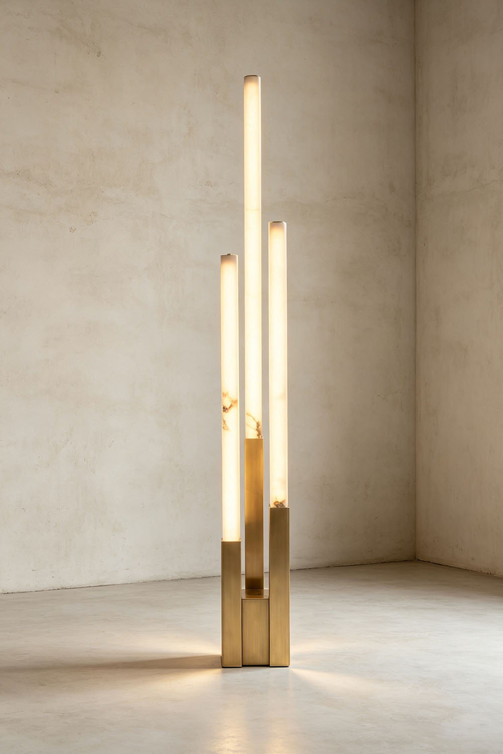 Gethin Triple Column Alabaster Floor Lamp | Natural Alabaster and Brass | Full view glowing softly against a warm neutral wall | Samu Lamp