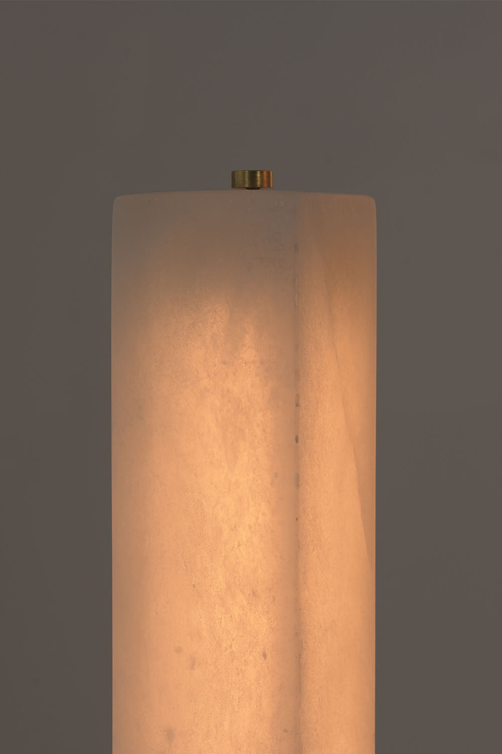 Gethin Triple Column Alabaster Floor Lamp | Natural Alabaster and Brass | Close-up view of the illuminated alabaster pillar top and brass finial | Samu Lamp