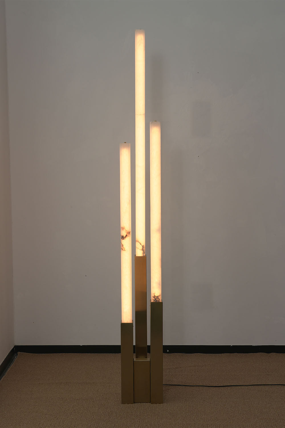 Gethin Triple Column Alabaster Floor Lamp | Natural Alabaster and Brass | Full view glowing brightly on a plain studio background | Samu Lamp
