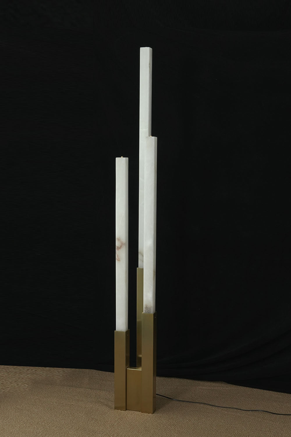 Gethin Triple Column Alabaster Floor Lamp | Natural Alabaster and Brass | Full view glowing softly against a warm neutral wall | Samu Lamp