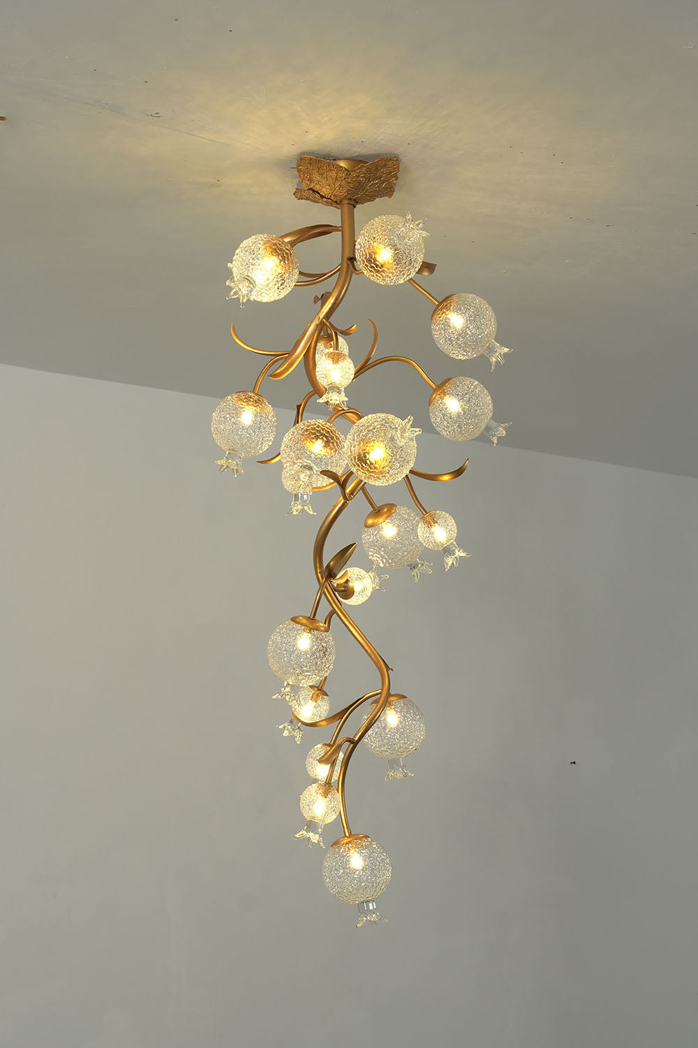 Grenaline Vine Chandelier | Brass and Crackle Glass | Full vertical profile lit against wall with warm glow | Samu Lamp