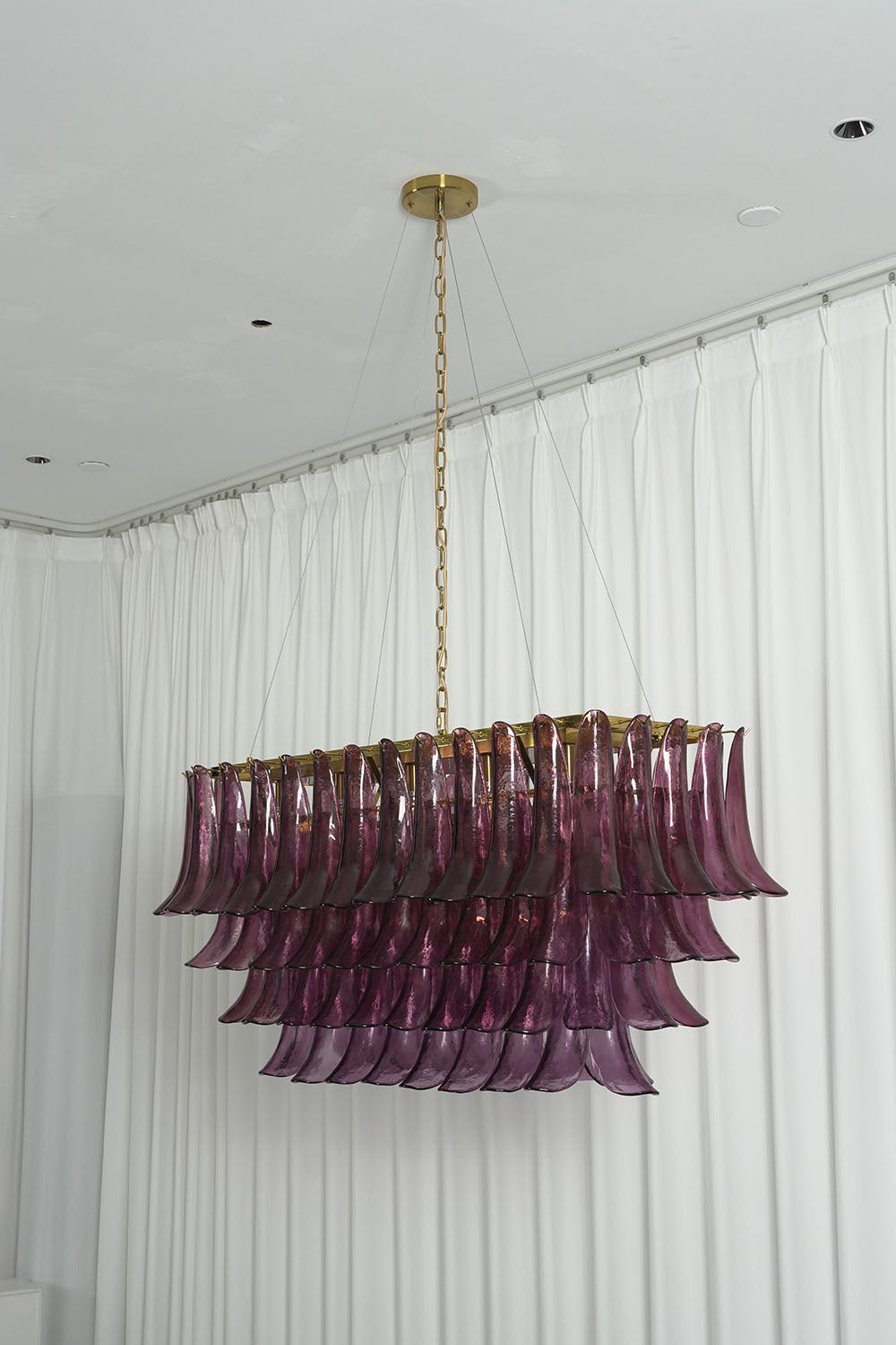 Ilvesse Amethyst Glass Petal Rectangular Chandelier | Amethyst Glass and Brass | Real-life side view glowing brightly near white window drapes | Samu Lamp
