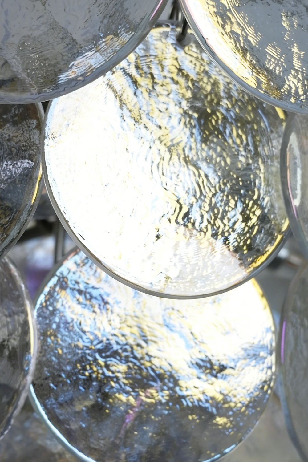 Lit iridescent glass discs detail | Glass | Close-up of glowing glass panels and hooks | Samu Lamp