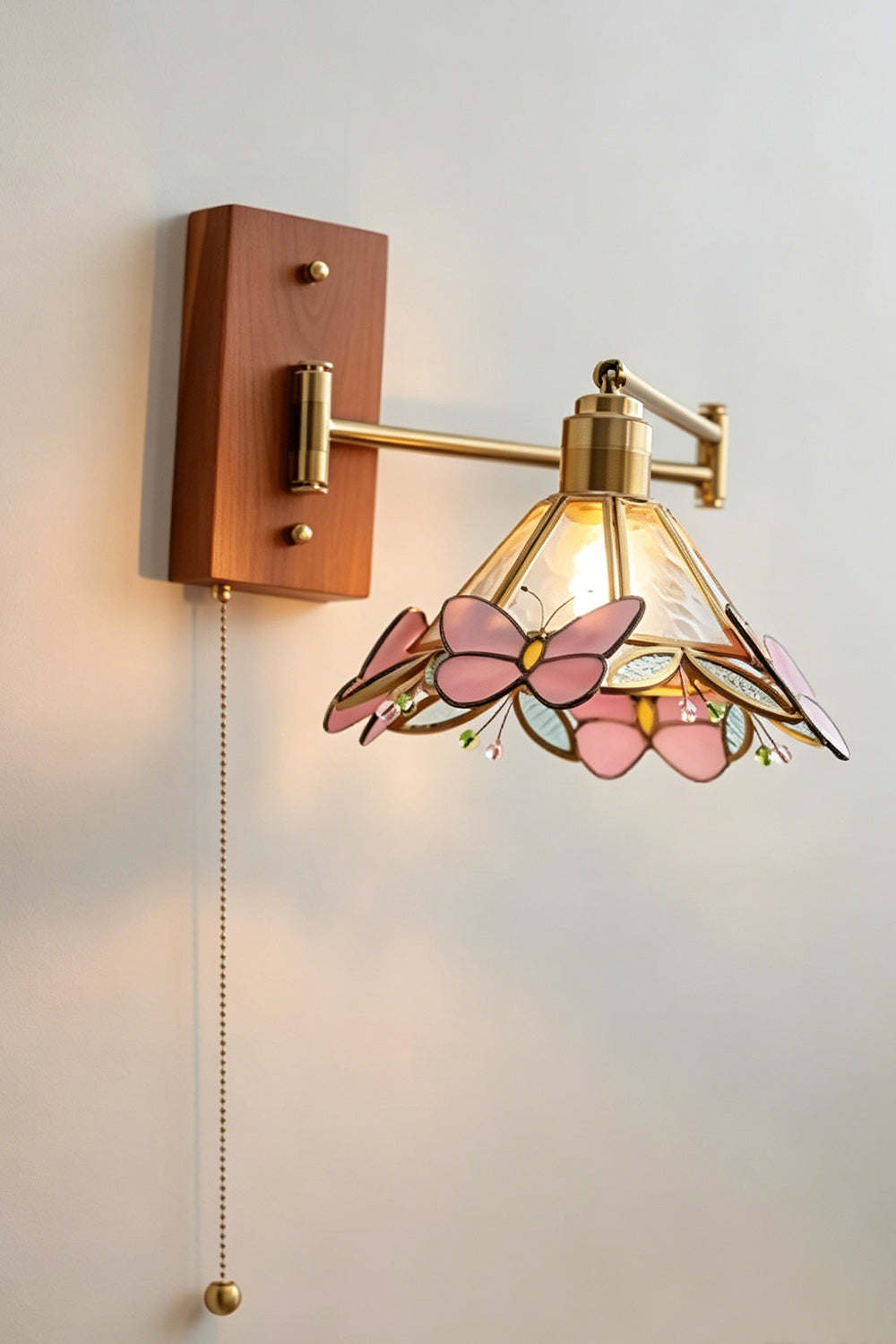 Iris Butterfly Stained Glass Wall Lamp | Stained Glass, Metal, Wood | Frontal perspective view of the fully illuminated stained glass wall lamp casting a soft warm backlight halo against a plain neutral wall | Samu Lamp