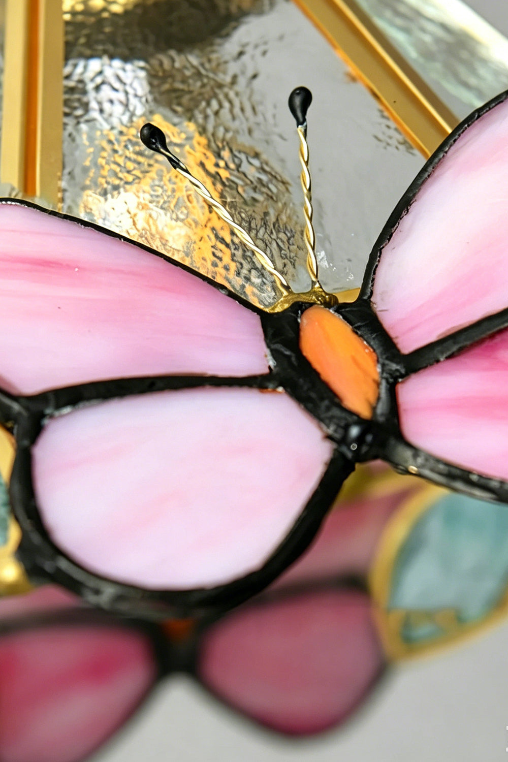 Iris Butterfly Stained Glass Wall Lamp | Stained Glass, Metal, Wood | Macro close-up shot highlighting the vibrant pink and orange stained glass panels, leaded solder lines, and delicate wire antennas of the butterfly motif | Detail shot | Samu Lamp