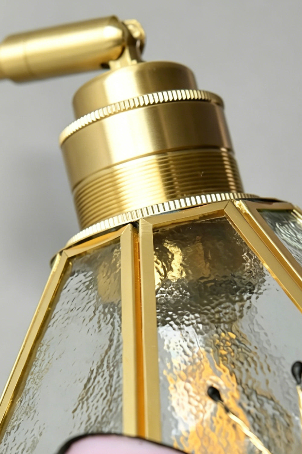 Iris Butterfly Stained Glass Wall Lamp | Stained Glass, Metal, Wood | Macro close-up view of the polished gold brass socket cap, adjustable joint hardware, and the upper edge of the textured clear hammered glass shade | Detail shot | Samu Lamp