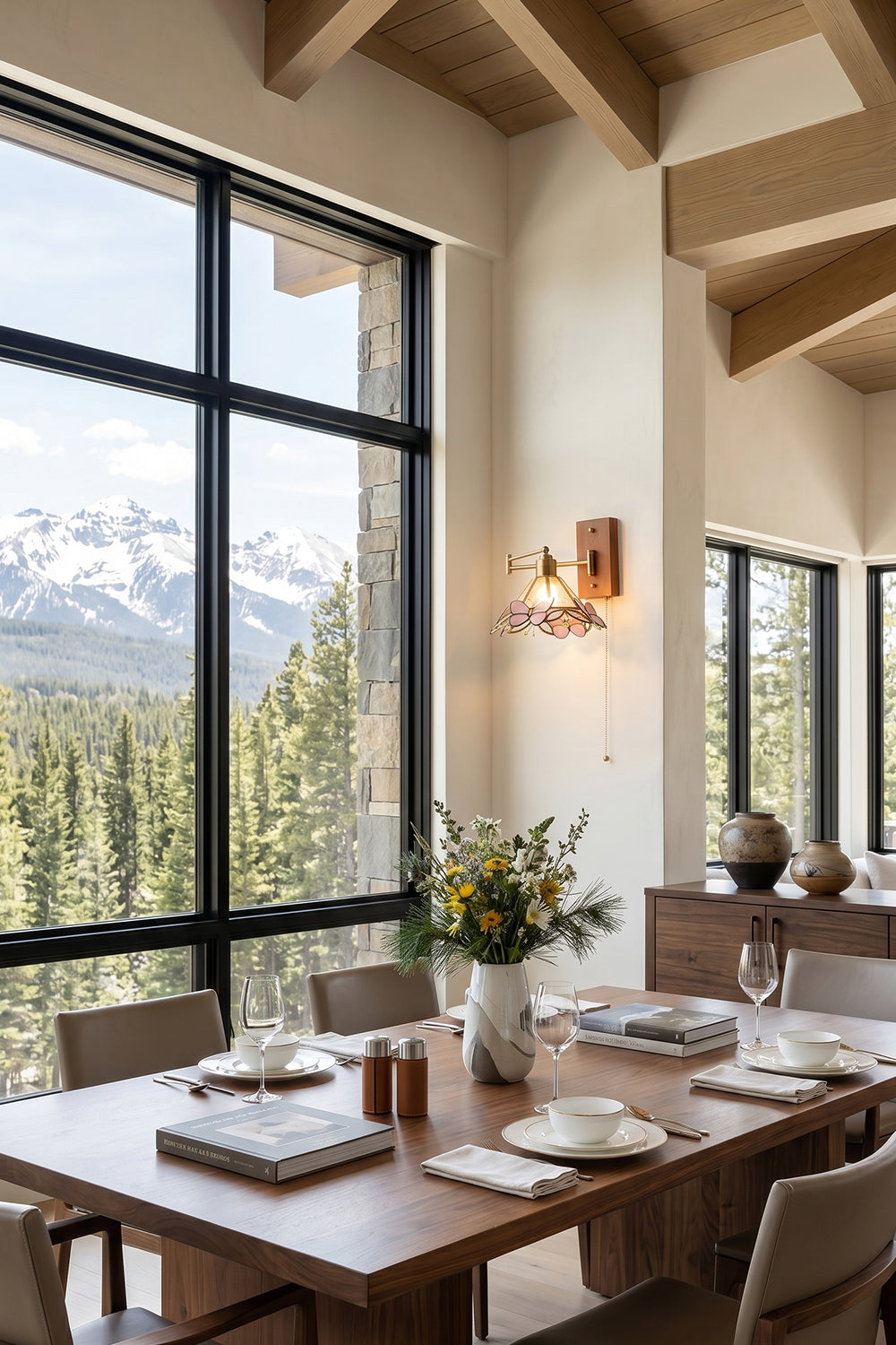 Iris Butterfly Stained Glass Wall Lamp | Stained Glass, Metal, Wood | Installed on a wooden wall in an alpine-style dining room, casting a warm glow next to a long dining table and large grid windows overlooking mountains | Samu Lamp