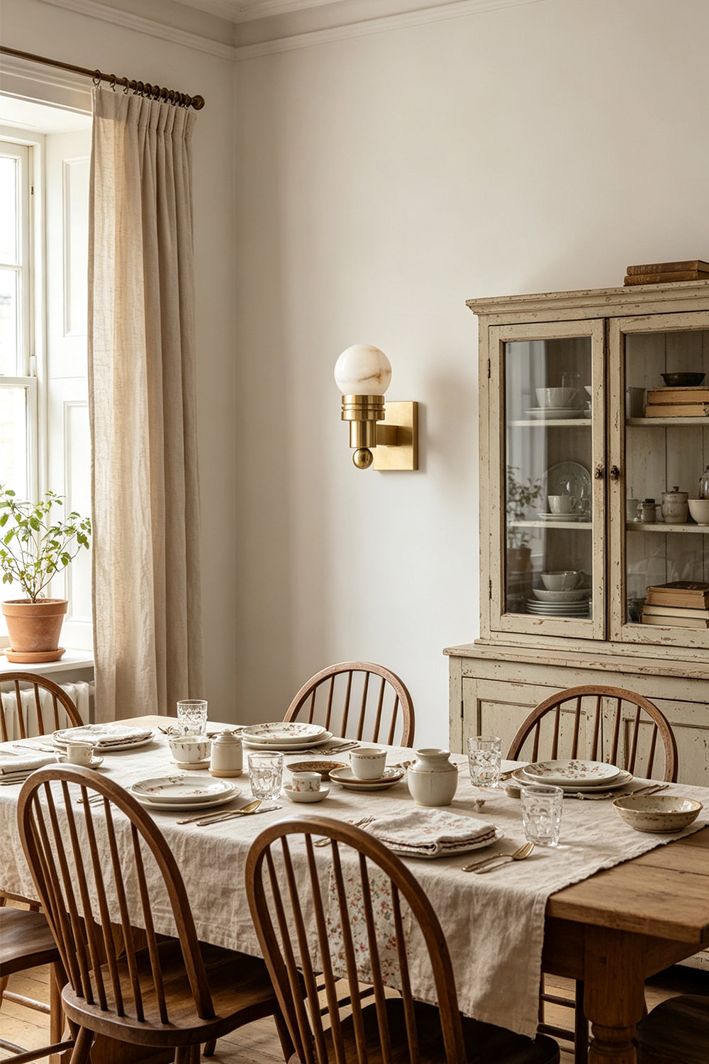 Isolde Alabaster Orb Wall Sconce | Natural Alabaster and Aged Brass | Illuminating a classic rustic dining room with a wooden dining table and chairs | Samu Lamp