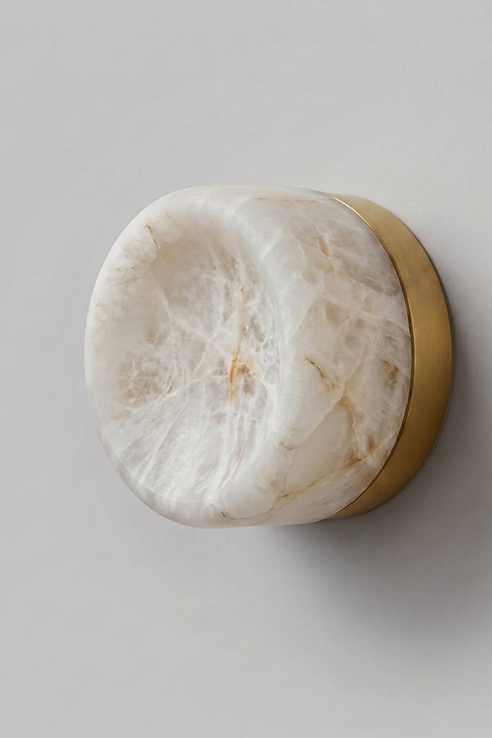 Isolde Concave Alabaster Disc Wall Sconce | Natural Alabaster and Brass | Studio close-up shot showing the natural stone veins and brass backplate on a light wall | Samu Lamp