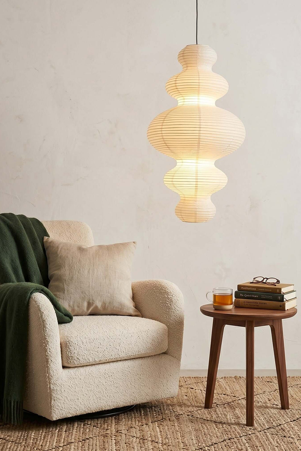 Isolde Stacked Paper Pendant Lamp | Textured Ribbed Paper | Casting soft light over a cozy reading corner with a plush cream armchair and side table | Samu Lamp