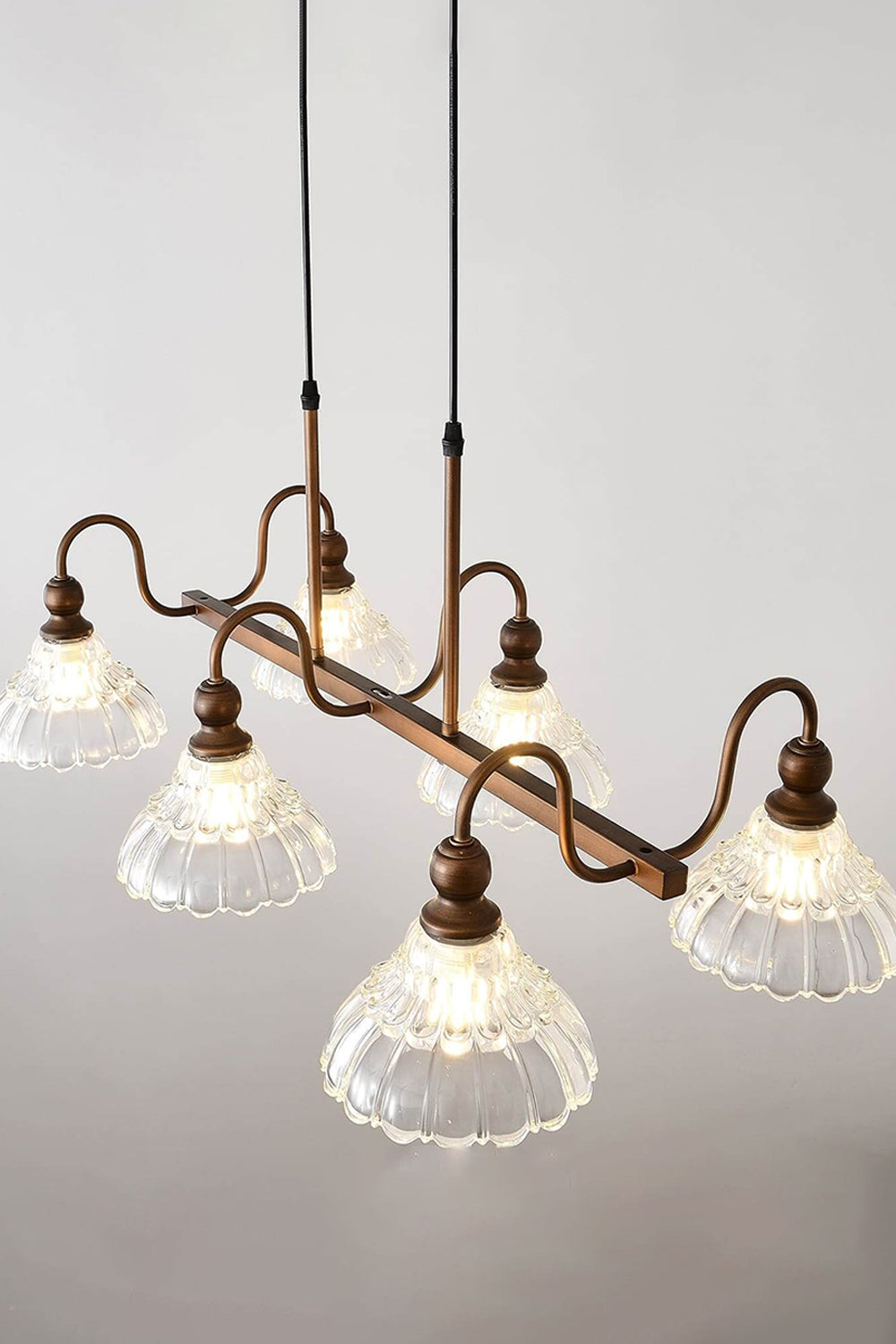 Isolde Vintage Glass Long Chandelier | High Angle Studio View | Studio perspective shot looking slightly down at the illuminated linear bronze and glass island fixture showcasing its elongated shape | Samu Lamp
