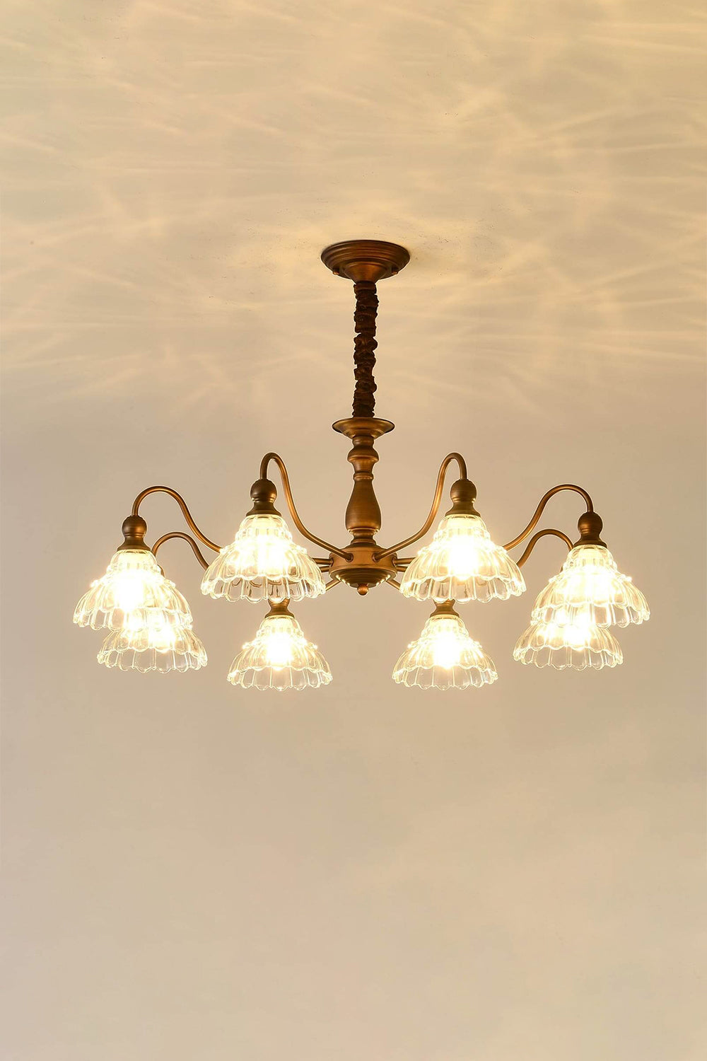 Isolde Vintage Scalloped Glass Chandelier | Warm Halo Effect | Staged studio shot of the illuminated glass chandelier projecting a beautiful golden light pattern onto a warm cream wall | Samu Lamp