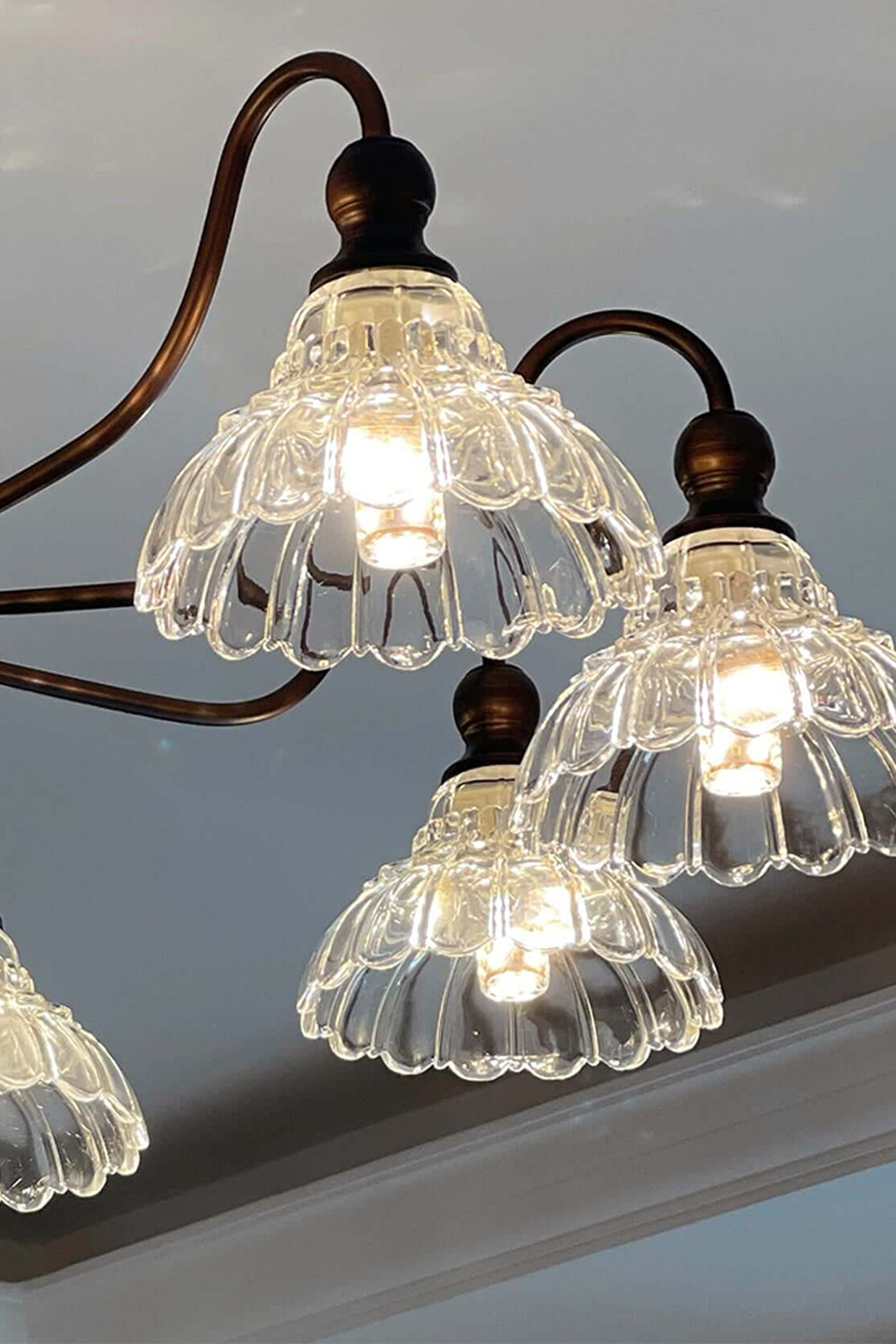 Isolde Vintage Scalloped Glass Chandelier | Looking Up View | Studio perspective view looking up at the illuminated ruffled clear glass shades radiating a bright warm glow | Samu Lamp